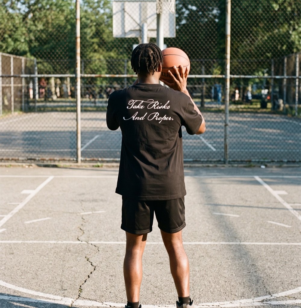 Joueur de dos avant un lancer franc au coucher du soleil, en t-shirt TRAP noir
