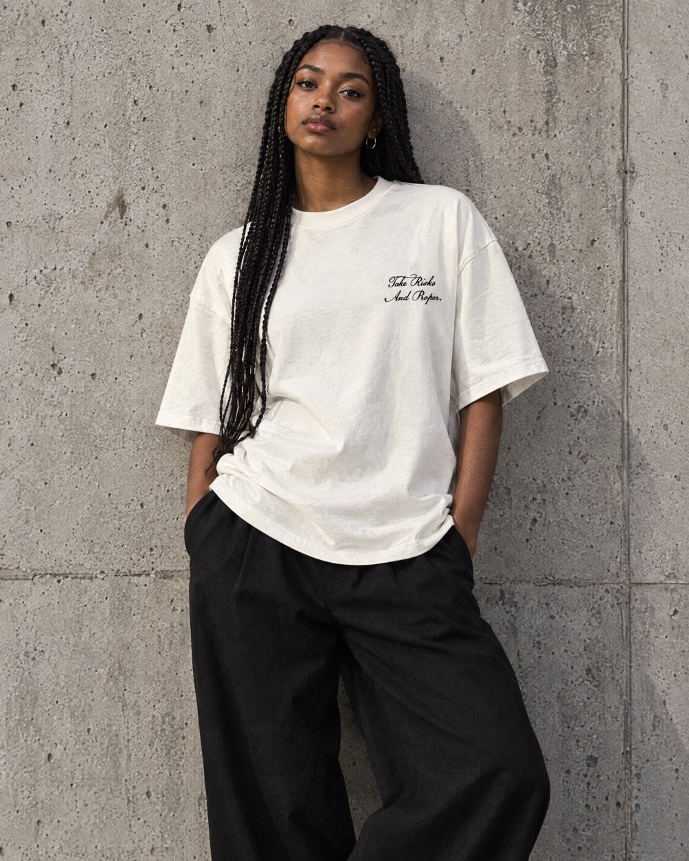 Jeune femme adossée à un mur en béton, en t-shirt TRAP blanc